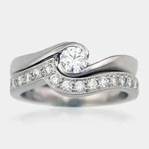 Handmade round brilliant cut diamond engagement ring with matching, fitted wedding ring in 18ct white gold and milgrain finish.