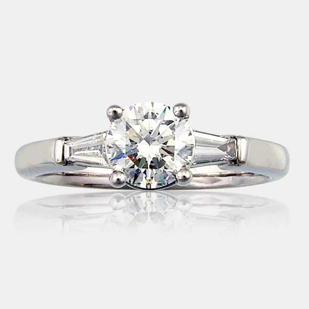 Round brilliant cut diamond engagement ring with tapered baguette shoulder diamonds.
