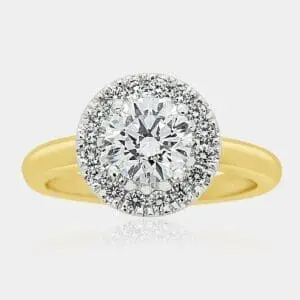 Two-tone, yellow gold ring featuring round brilliant cut centre diamond and halo of round diamonds in a white gold setting.