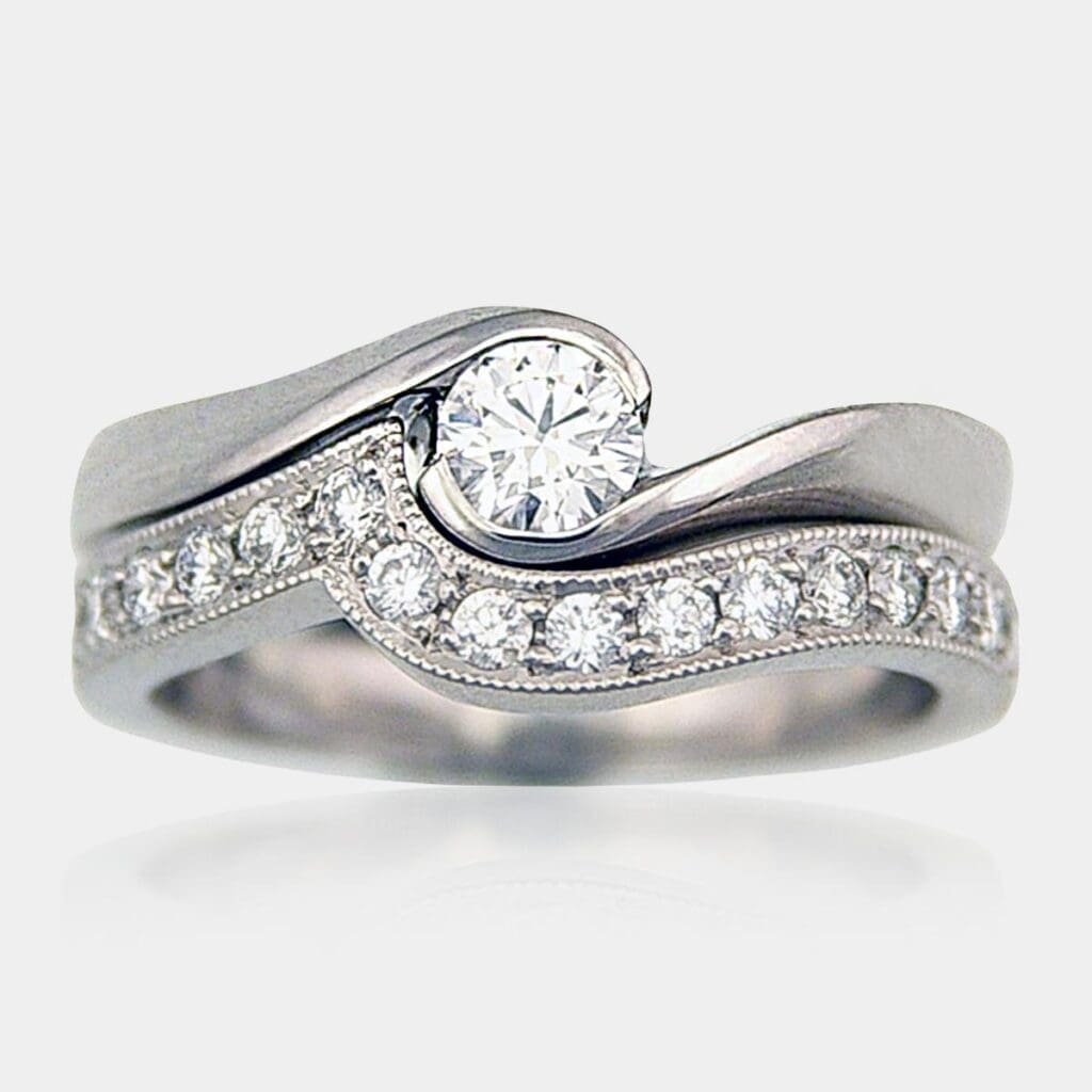 Handmade round brilliant cut diamond engagement ring with matching, fitted wedding ring in 18ct white gold and milgrain finish.
