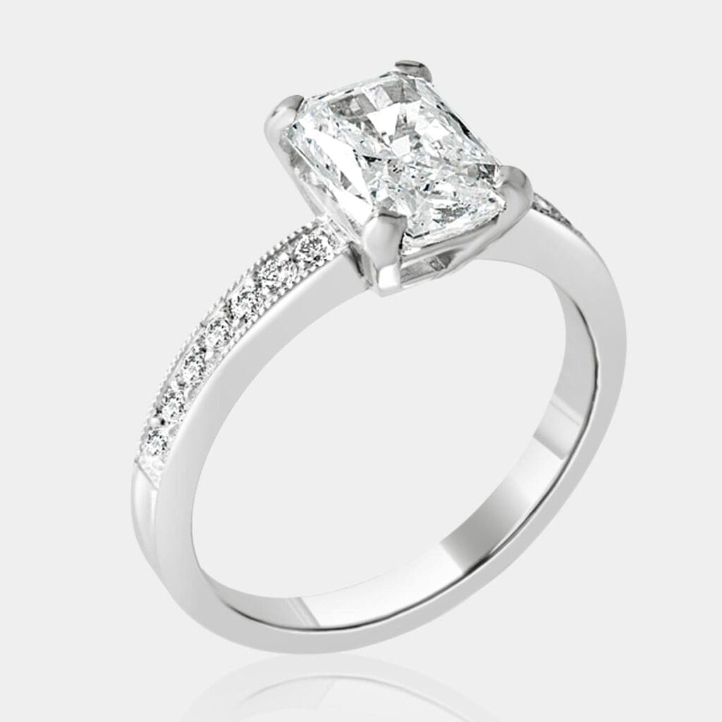Handmade diamond engagement ring in 18ct white gold with a stunning 1.80 carat radiant cut diamond and bead set shoulder diamonds and milgrain detail.