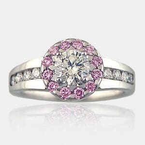 Round brilliant cut diamond ring with halo of pink diamonds. Tapered band channel set with round diamonds.