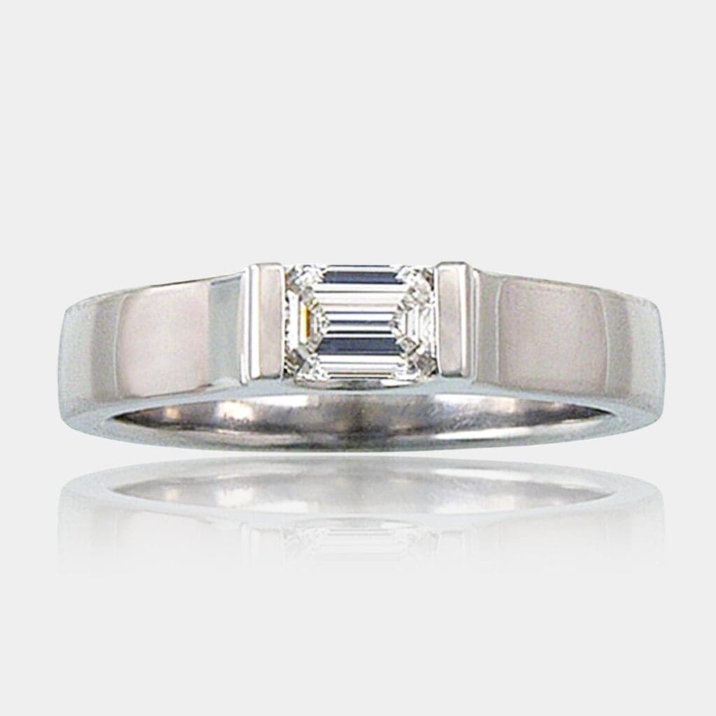 0.60 carat Emerald cut solitaire diamond ring, bar set in an upswept white gold band.