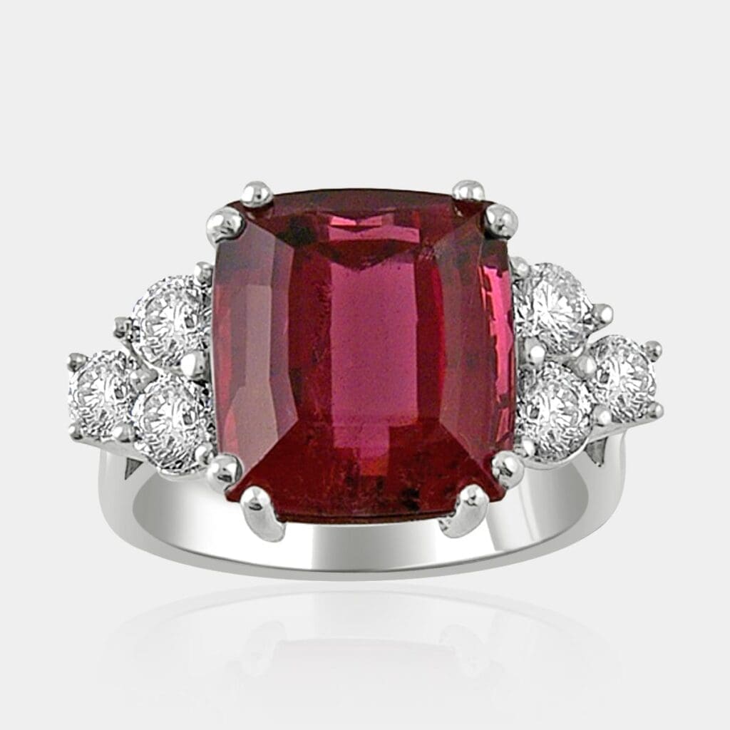Cushion cut dark pink-red tourmaline ring with round brilliant cut diamond cluster in 18ct white gold.