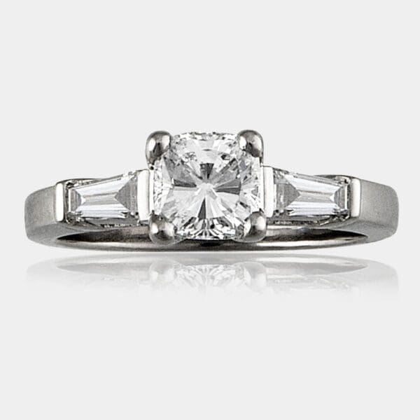 Cushion cut diamond engagement ring with shoulder baguettes.