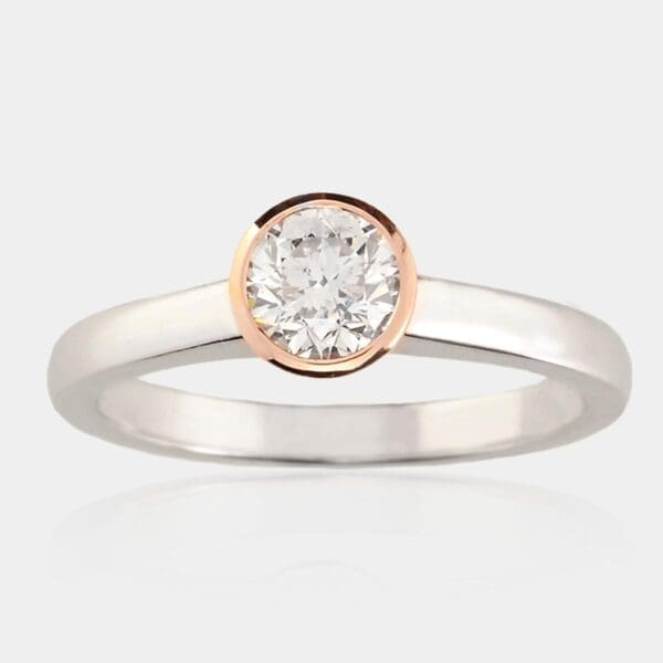 Solitaire diamond engagement ring with rose gold bezel setting and white gold band.