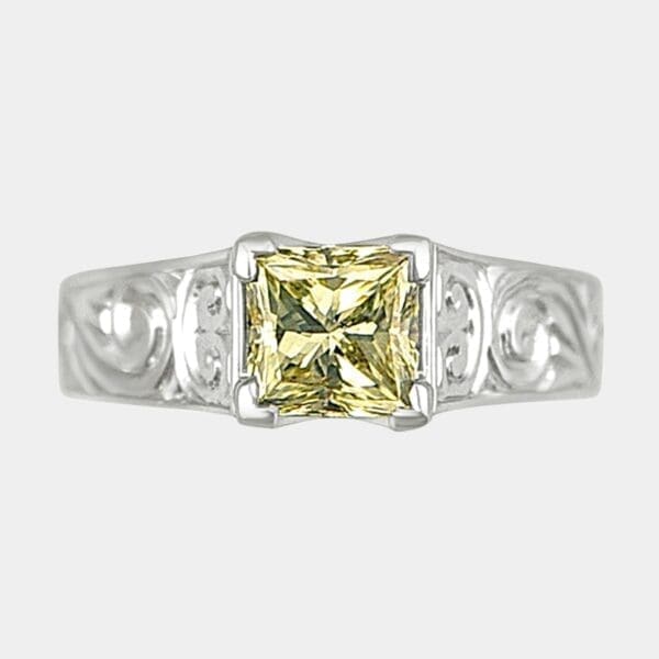 Handmade princess cut yellow diamond engagement ring V claw set in white gold with engraving in the band.