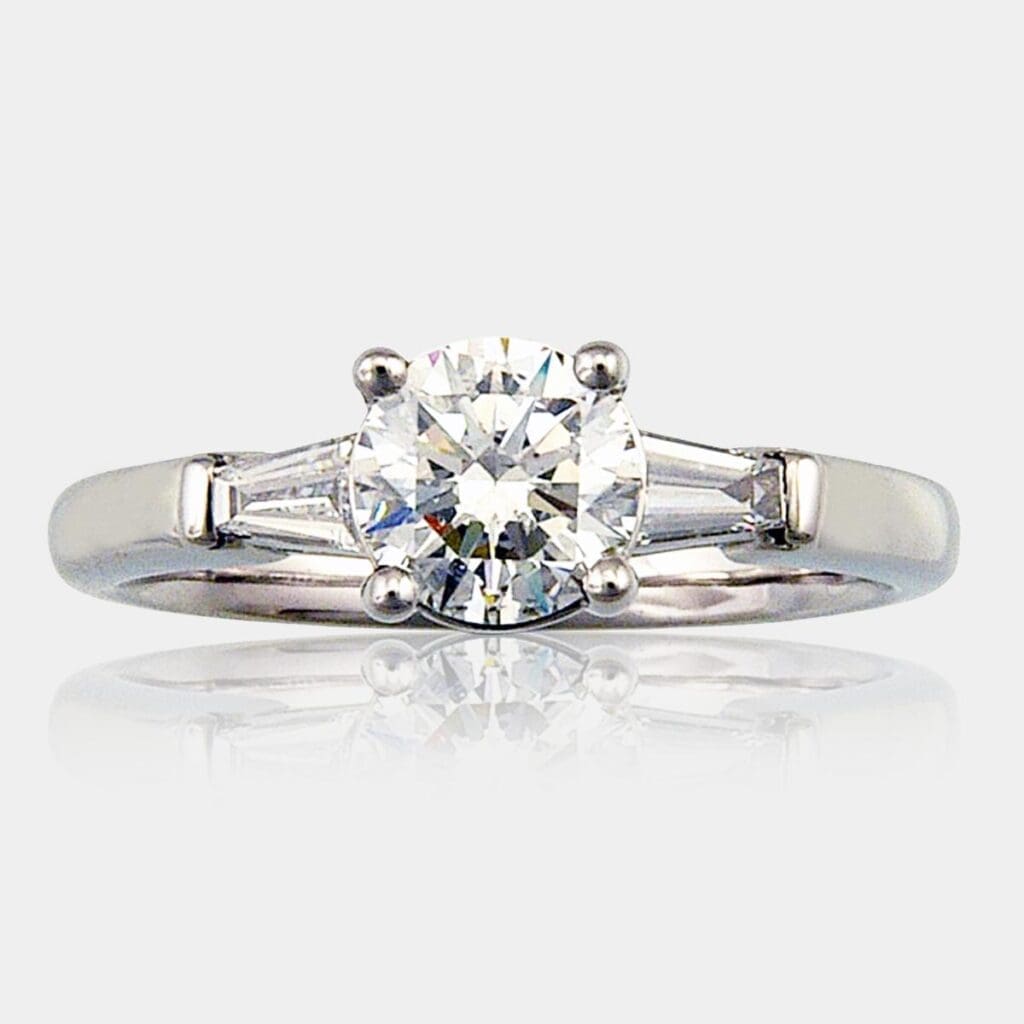 Round brilliant cut diamond engagement ring with tapered baguette shoulder diamonds.