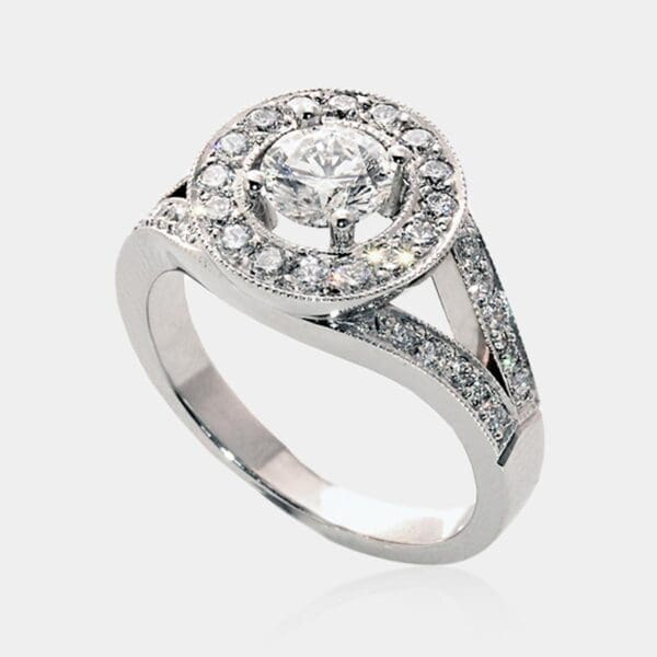Handmade, round brilliant cut diamond halo engagement ring with bead set diamonds in split shank and milgrain detail.