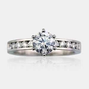 Handmade 18ct white gold round brilliant cut diamond engagement ring with channel set shoulder diamonds.