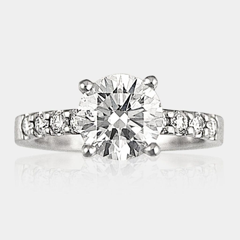 Round brilliant cut engagement ring with share claw shoulder diamonds.