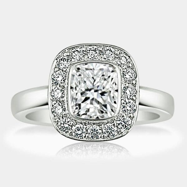 Cushion cut diamond engagement ring with round brilliant cut diamond halo in a plain, white gold band.