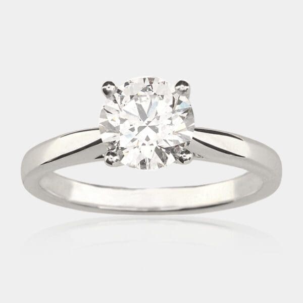 Solitaire diamond engagement ring with four claw setting in white gold, tapered band.