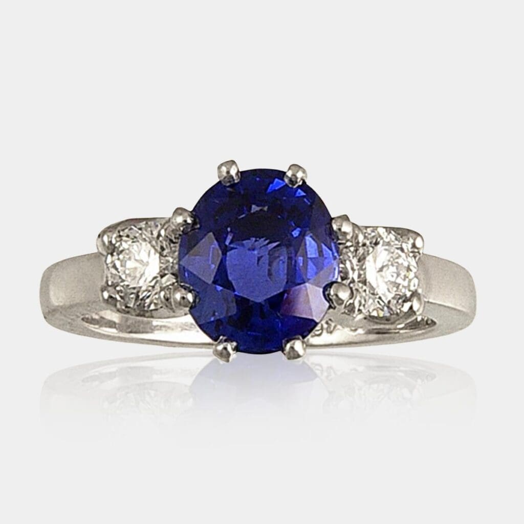 3 stone ring featuring oval cut blue sapphire & 2 x 0.25 carat round brilliant cut diamonds.