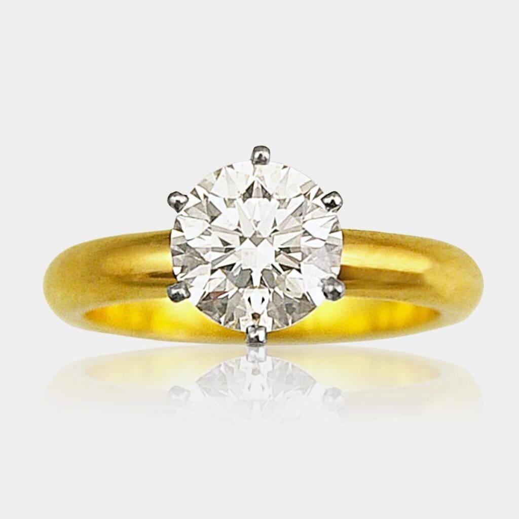 Round brilliant cut solitaire diamond engagement ring with six claw Platinum setting and 18ct yellow gold band.