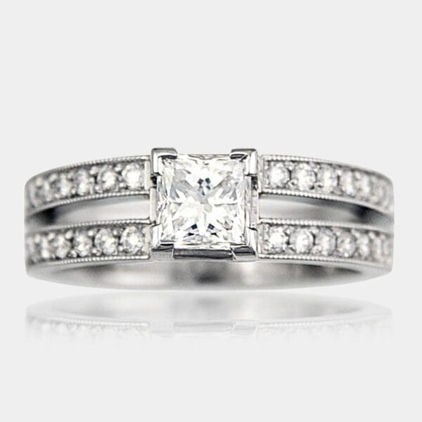 Handmade princess cut diamond engagement ring with split band, bead set with round diamonds and milgrain finish.