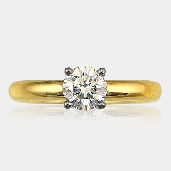 Handmade round brilliant cut solitaire diamond engagement ring with four claw 18ct white gold setting and yellow gold band.