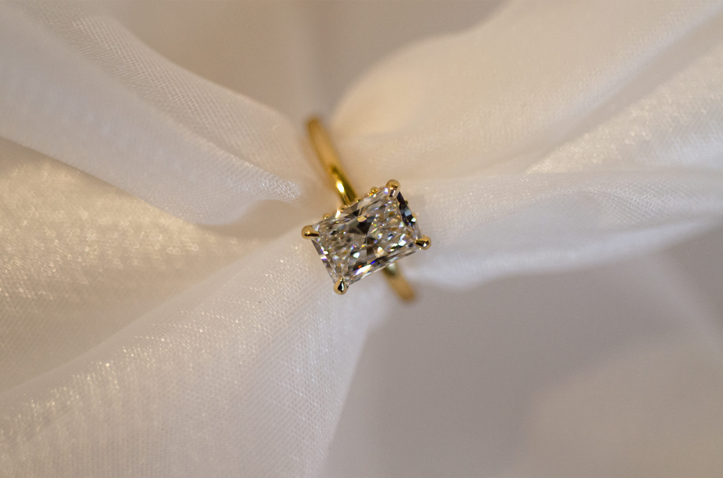 Emerald cut diamond engagement ring with hidden halo in a yellow gold band